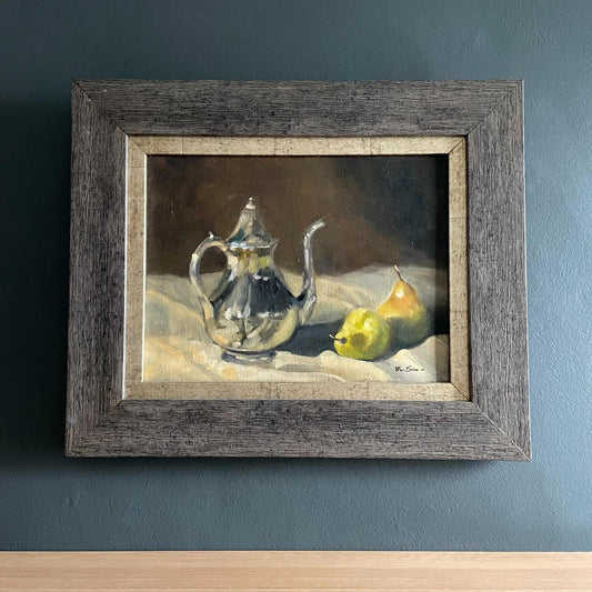 Beautiful oil painting of a silver coffee pot styled next to two pears on a tablecloth, framed in gold edging and a wooden frame.