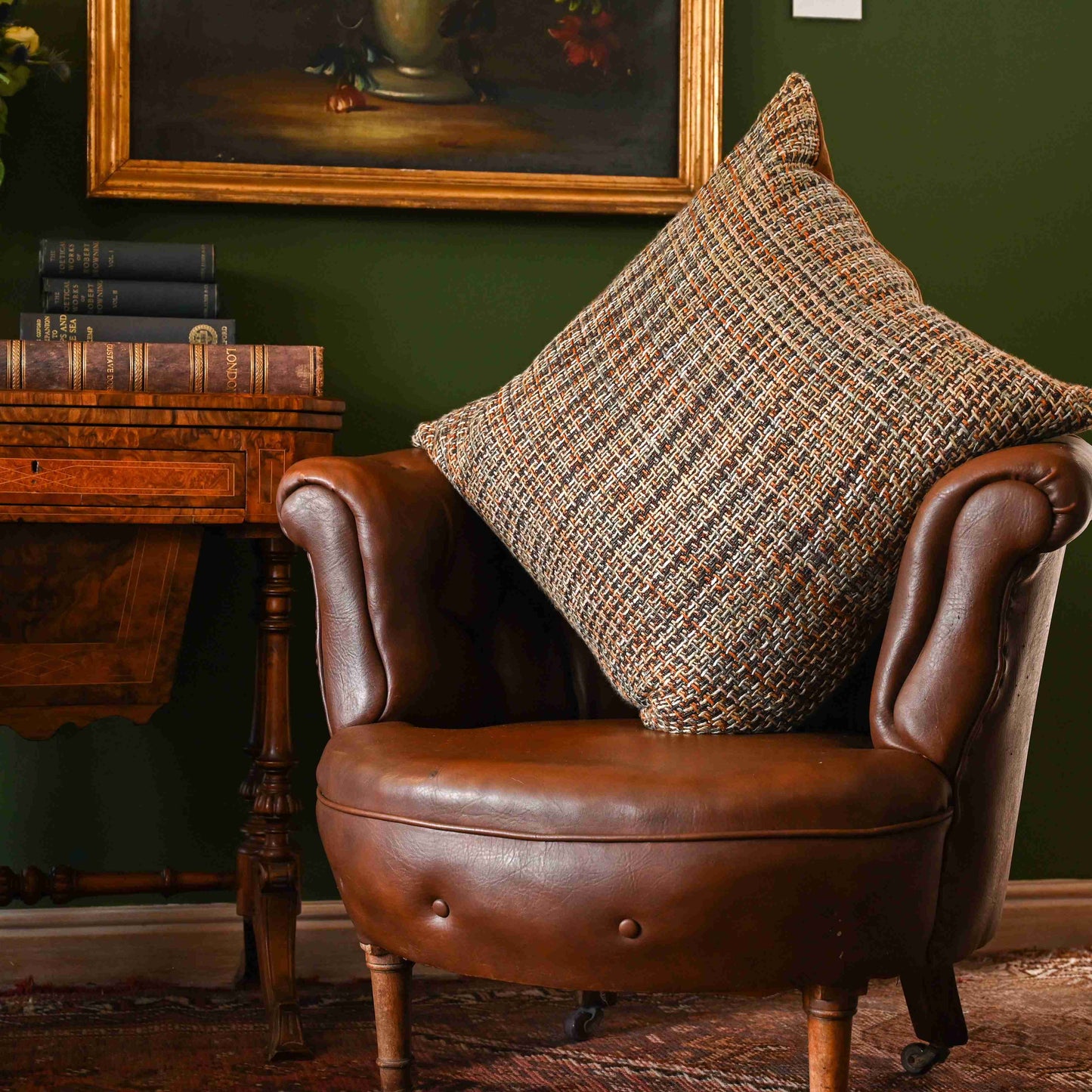 The Albion scatter cushion from the Scottish Heritage Collection on an antique leather sofa styled with antique collectibles