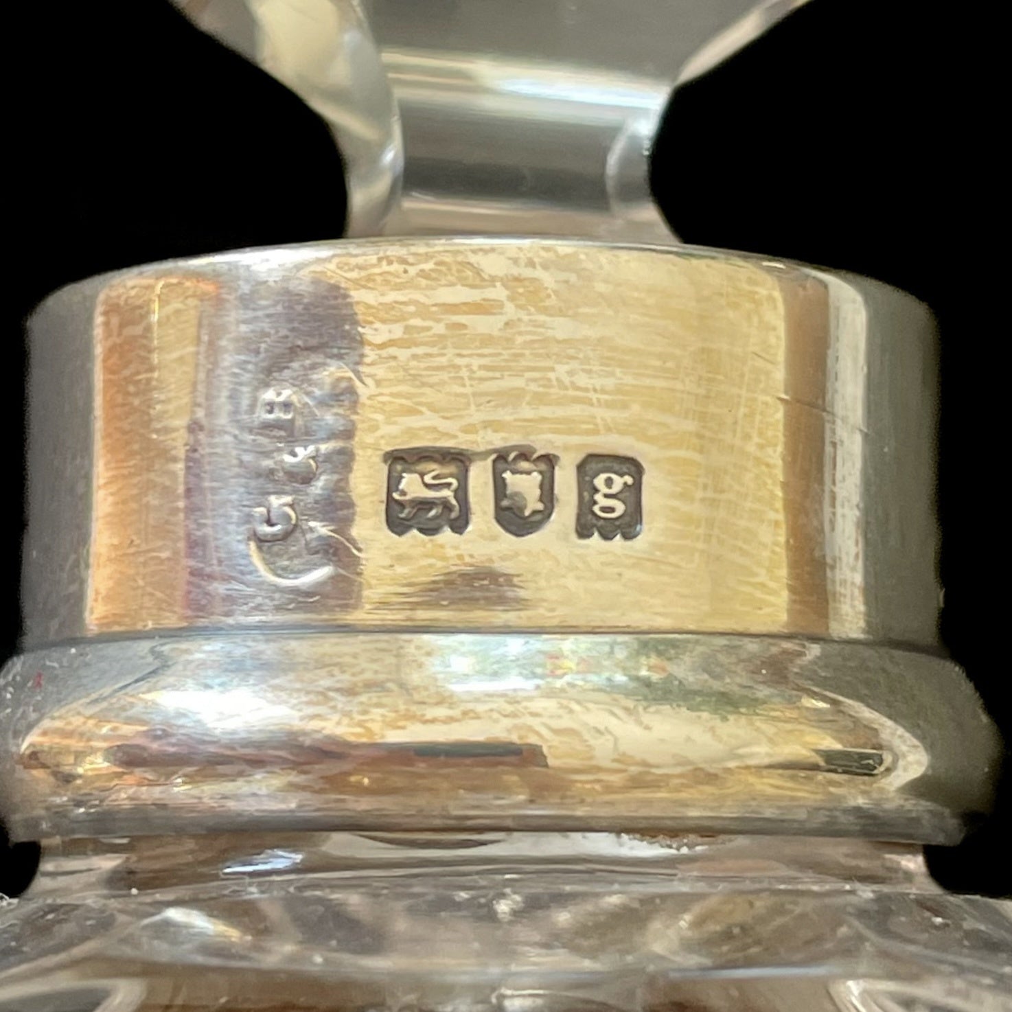 Close-up of a silver and gold ring with hallmarked text on a clear background