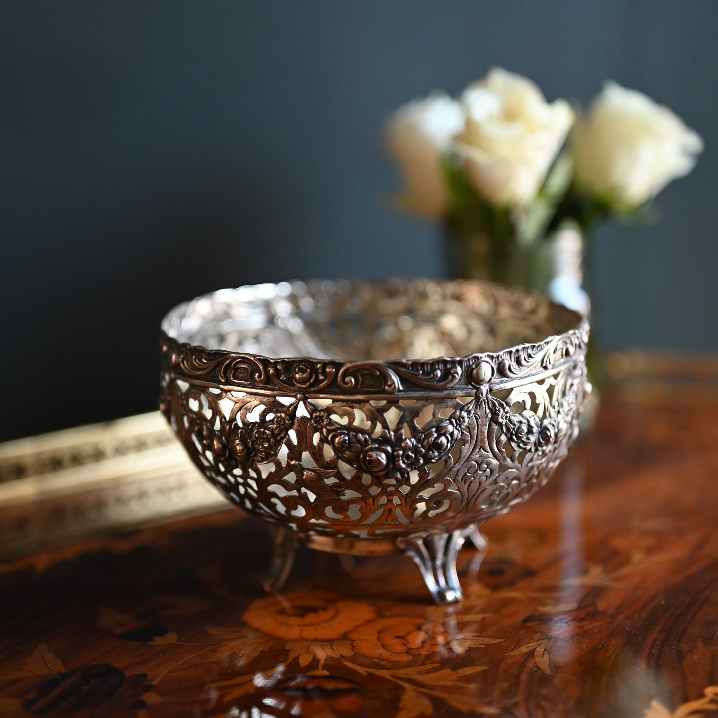 A romantic piece of early 20th-century craftsmanship, this German silver bowl features delicate openwork with swags of roses, birds in flight, and scrolling detail.