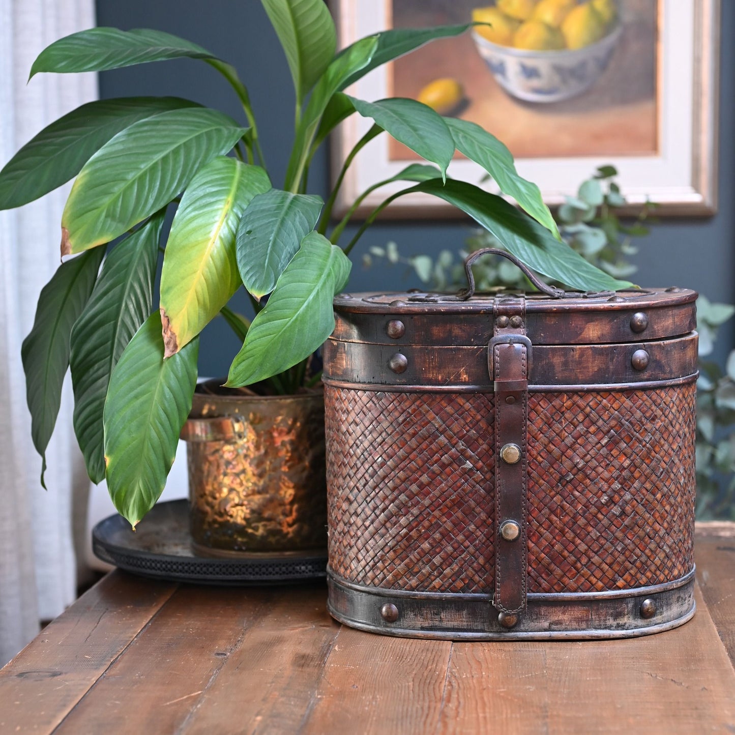 This antique storage box blends warm wood, woven lattice detail, and aged leatherette straps for a richly textured, timeworn look.