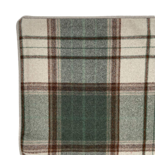 Close-up of a plaid fabric with green, brown, and beige colors on a white background