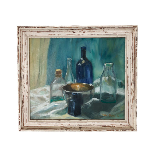 Framed still life painting with bottles and a bowl on a tablecloth.