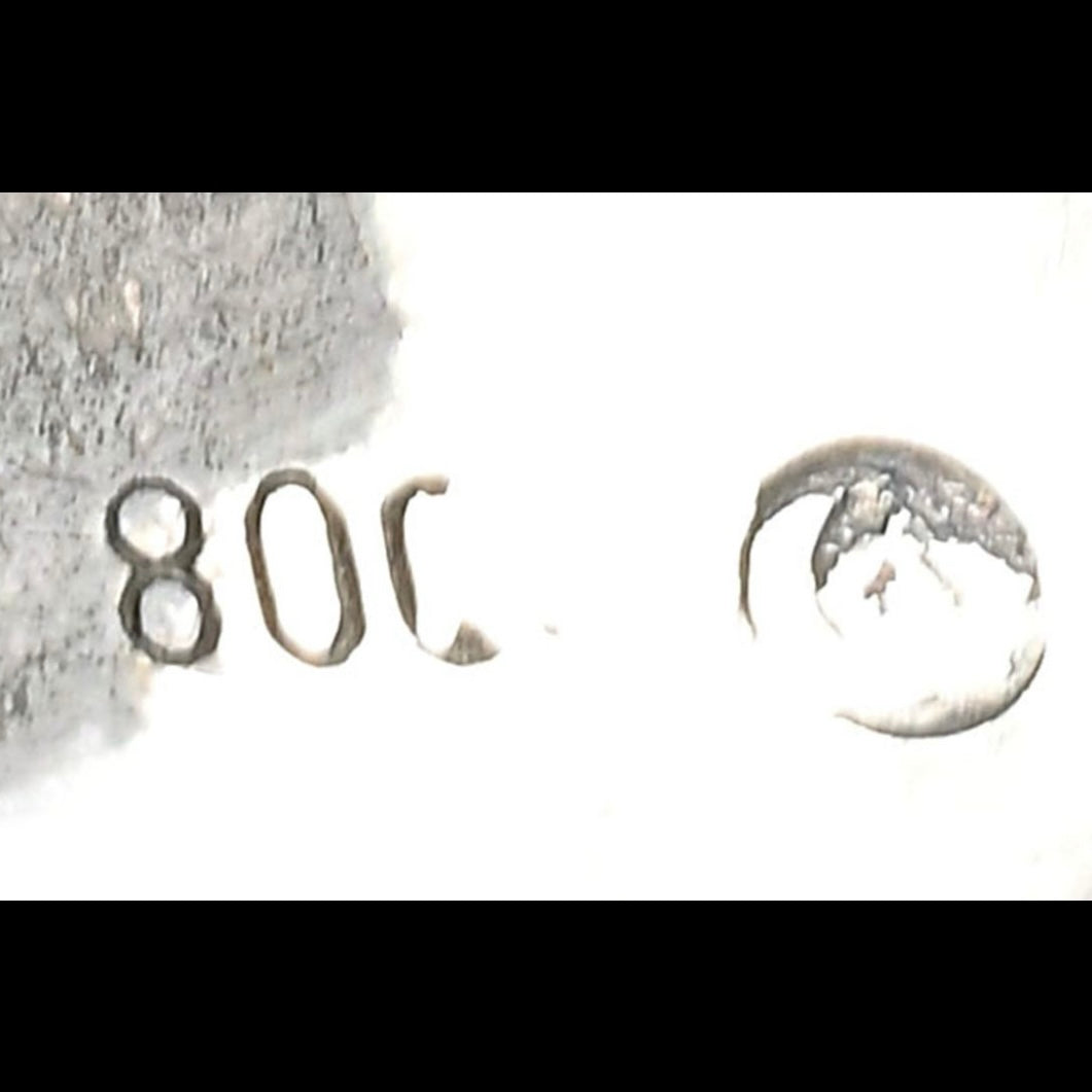 Close-up of a silver earring with a number '808' and a moon design on a white background.