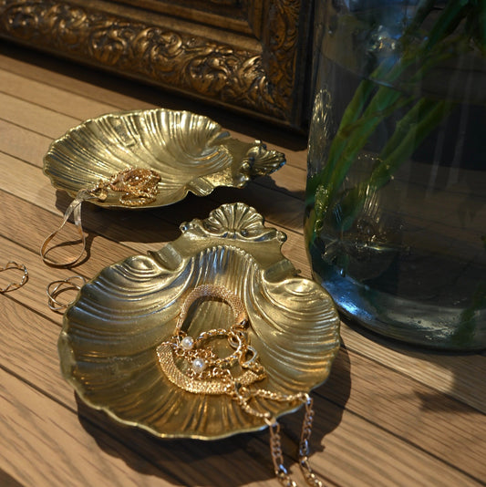 A pair of vintage shell dishes ,cast in gleaming brass with softly scalloped edges and ornate detailing at the base.