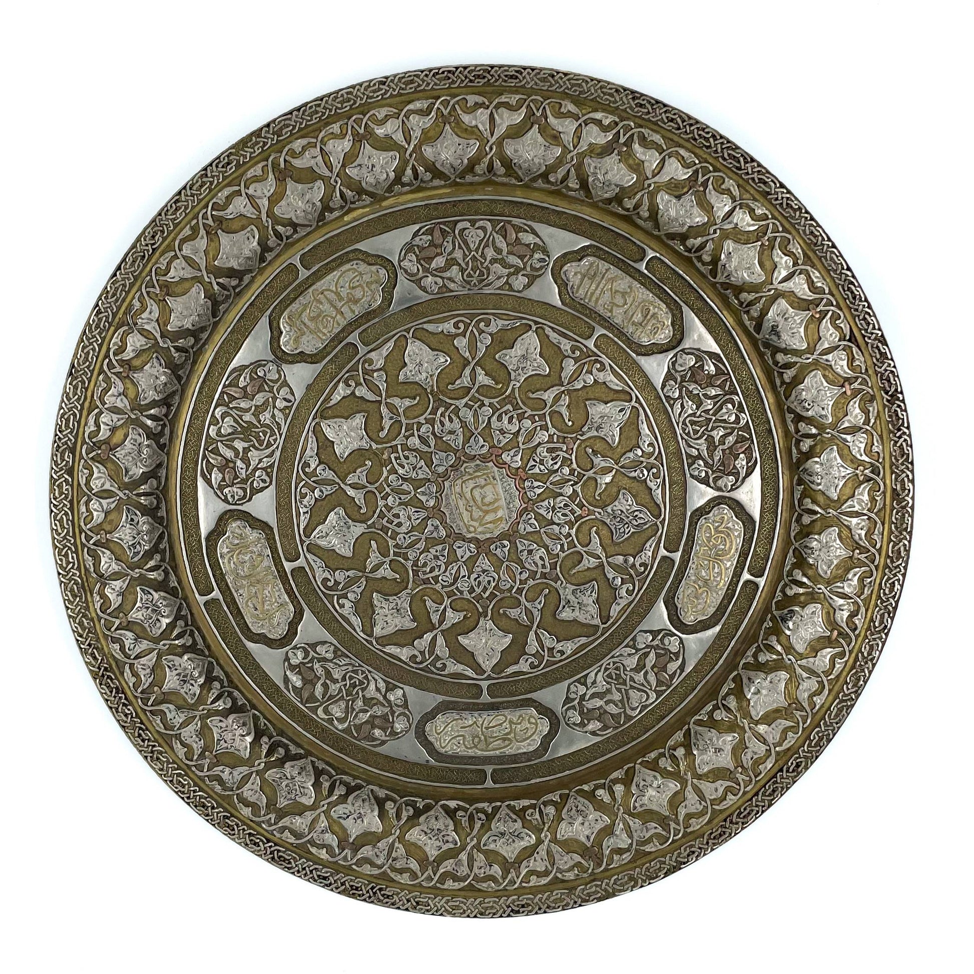 A solid ornate and intricately designed Persian metalwork tray or wall plate showcases detailed geometric patterns and calligraphy, made from a combination of brass, copper and silver.
