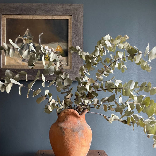 Beautiful oil painting of a silver coffee pot styled next to two pears on a tablecloth, framed in gold edging and a wooden frame.