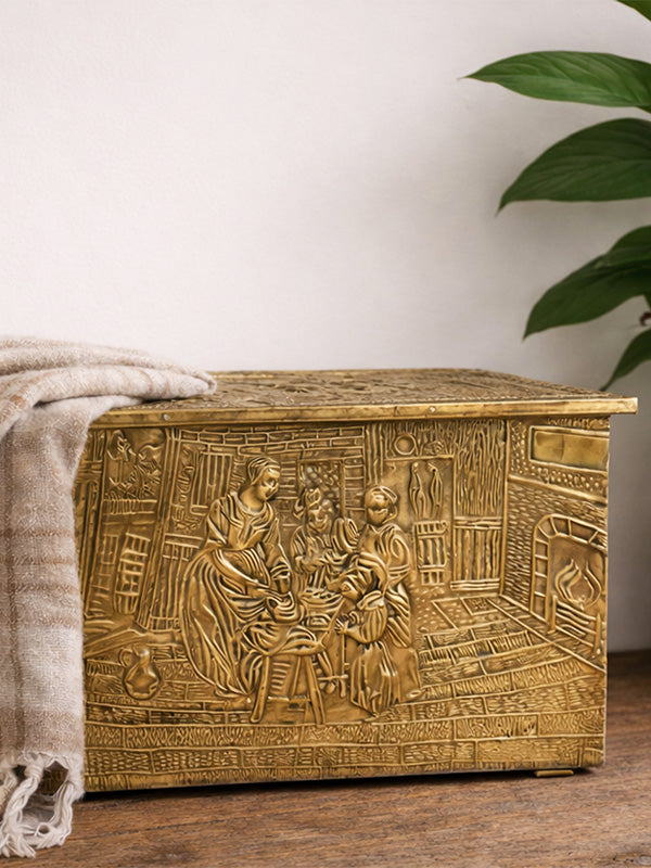 Antique brass decorative storage box with intricate carvings on a wooden surface.