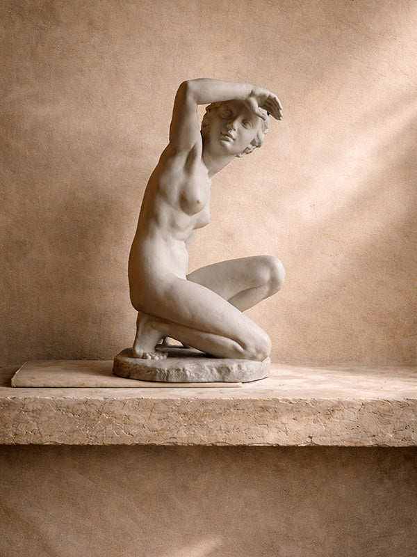 Vintage blanc de Chine porcelain statue of a nude figure on a pedestal against a beige wall