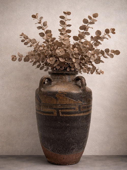 Antique Chinese stoneware vase with floral arrangement against a neutral background