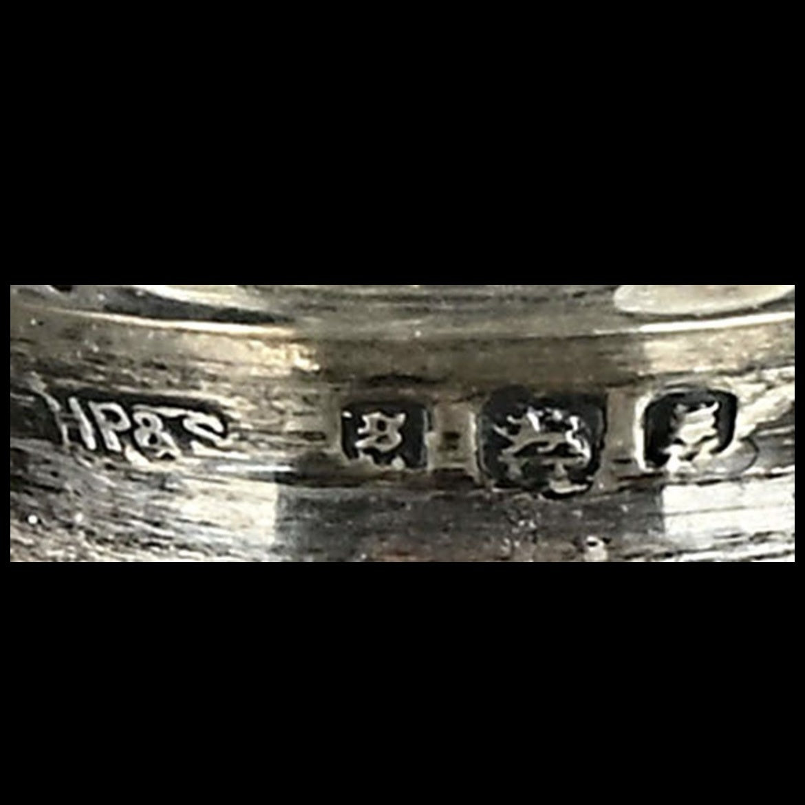 Close-up of a silver ring with engraved text on a black background