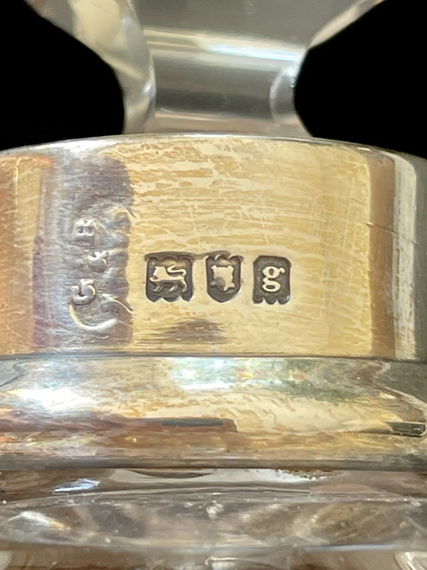 Close-up of hallmarks on silver neck of antique perfume bottle with engraved text and symbols.