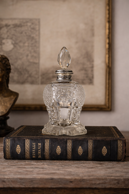 Antique Perfume bottle with silver cap on an old book, with a blurred map in the background