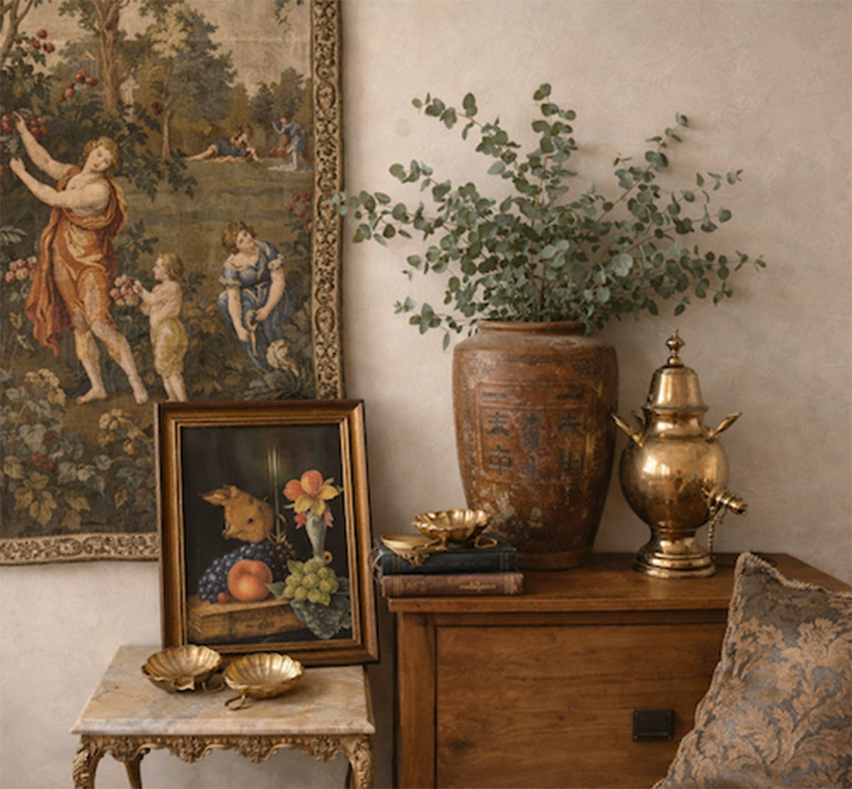 Decorative interior scene with antique paintings, a vase, and a lamp on a wooden table.
