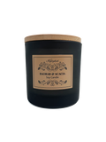 Black candle with a wooden lid and decorative label on a white background