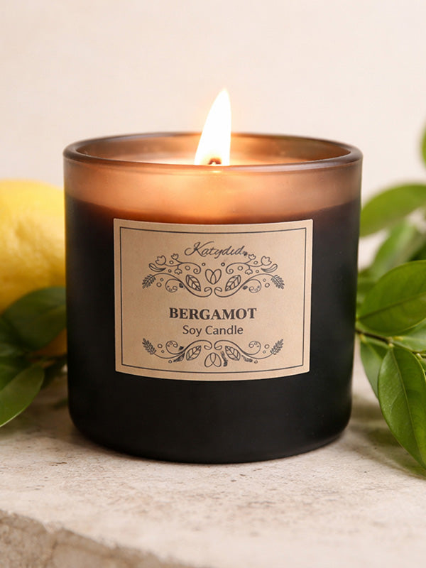 Scented candle labeled 'Bergamot' with a lemon and leaves in the background