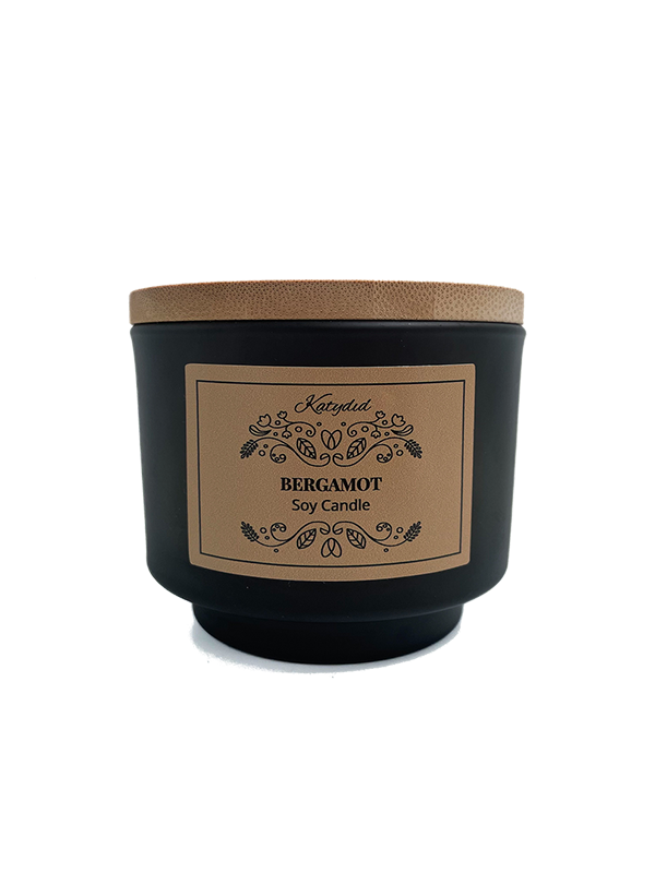 Black candle with a wooden lid and decorative label on a white background