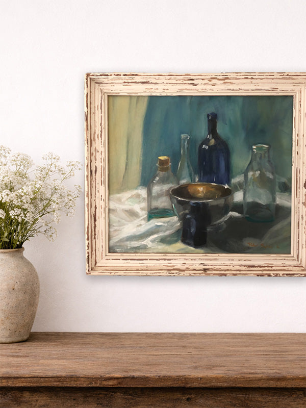 Framed still life painting on a wooden shelf with a vase of flowers.