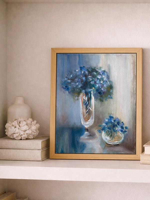 Framed painting of blue flowers on a shelf with decorative items.