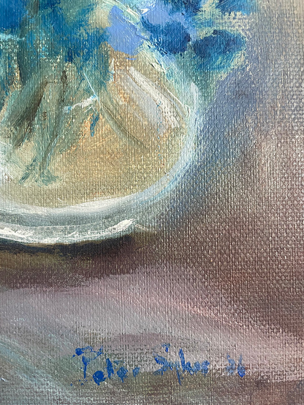 Close-up of an original oil painting of blue flowers in a vase, signed. 
