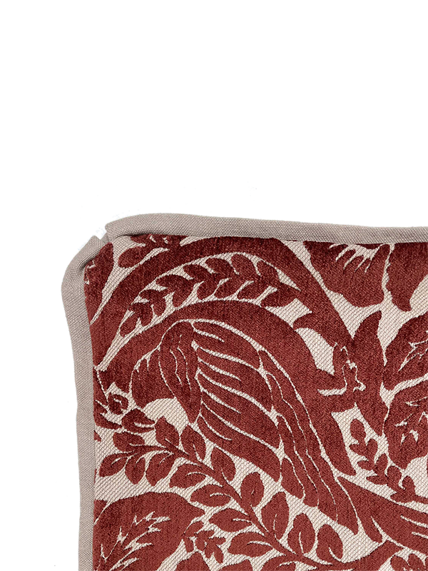 Close-up of a fabric with red bird and leaf pattern on a beige background
