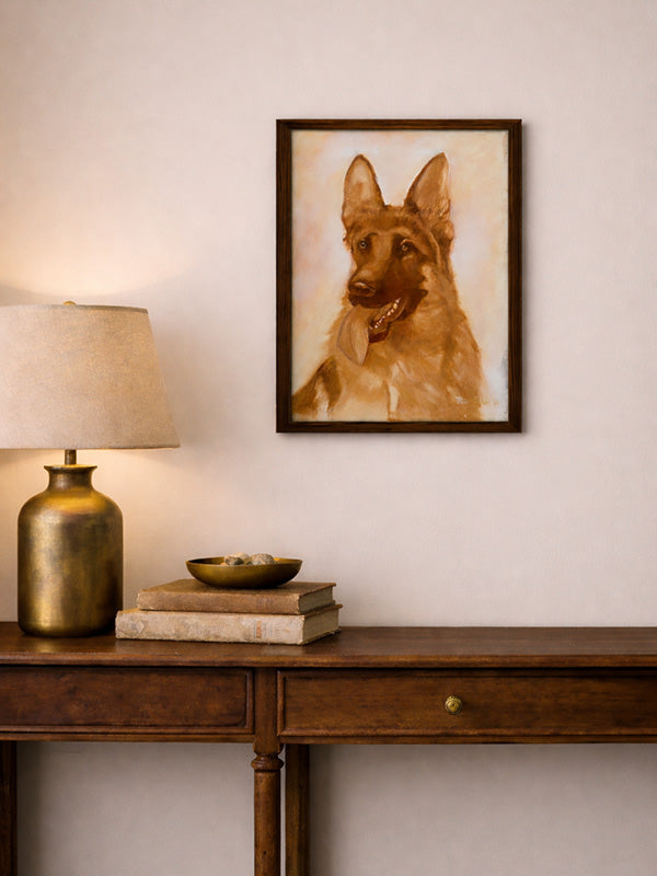 Framed portrait of a dog on a wall above a wooden console table with a lamp and books.
