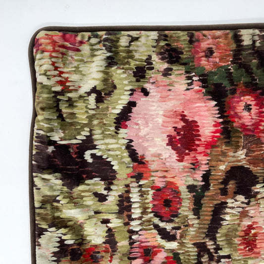 Close-up of a floral patterned fabric with pink, green, and brown colors on a white background.