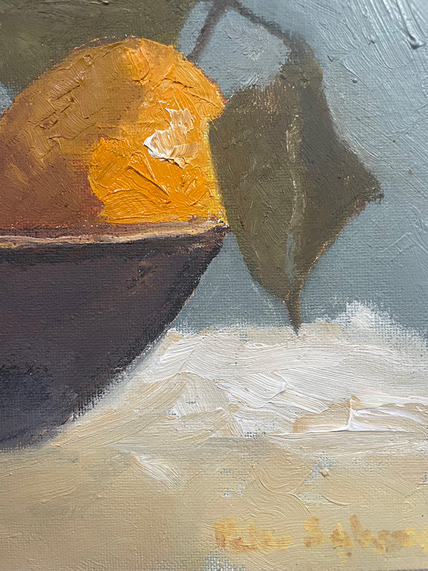 Close-up of a painting with lemons  and leaf on a textured surface
