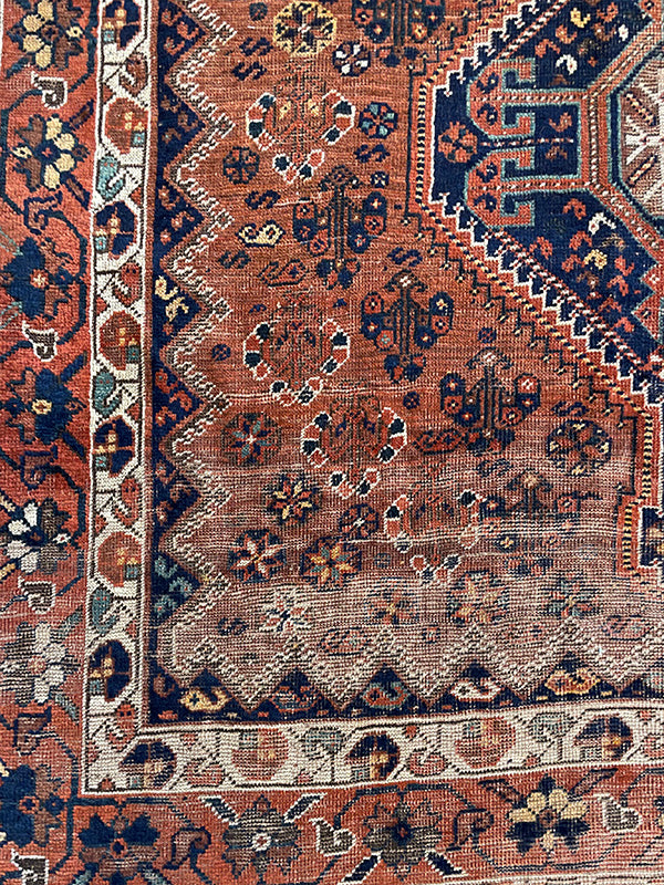 Close-up of an intricately patterned rug with a focus on the border and central design.