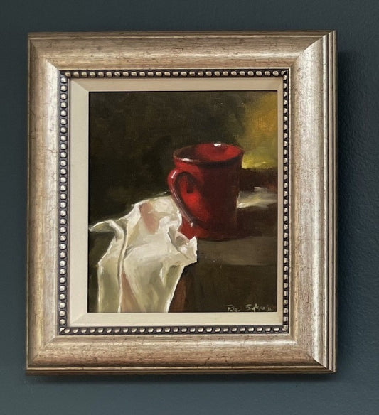 Framed painting of a red mug and white cloth on a dark background