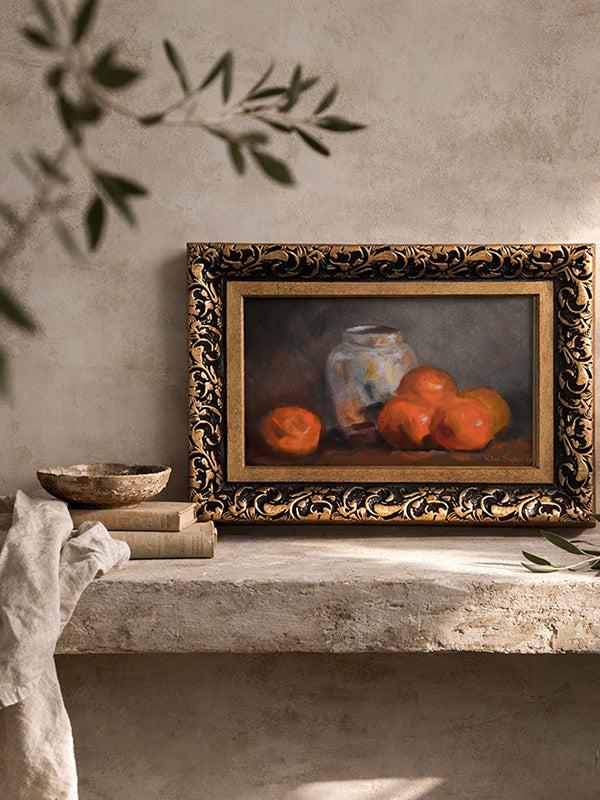 Framed still life painting of oranges on a stone surface with a textured wall background
