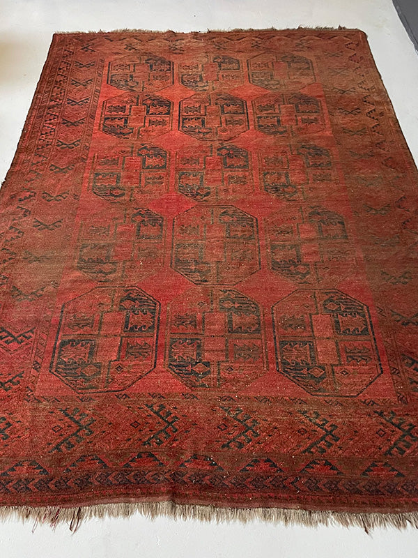 Red patterned rug with black geometric designs on a white background