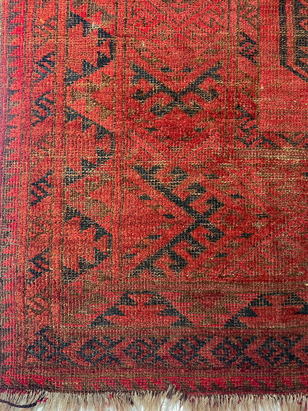 Red and black patterned rug with fringed edge