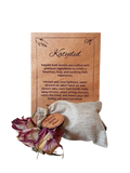 Katydid bath bomb packaging with wooden label and dried rose on a white background