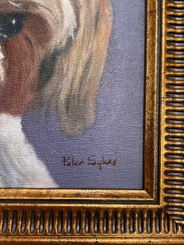 Close-up of a framed painting of a dog's face with a gold frame.