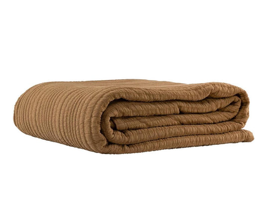 Folded nutmeg coloured blanket on a white background