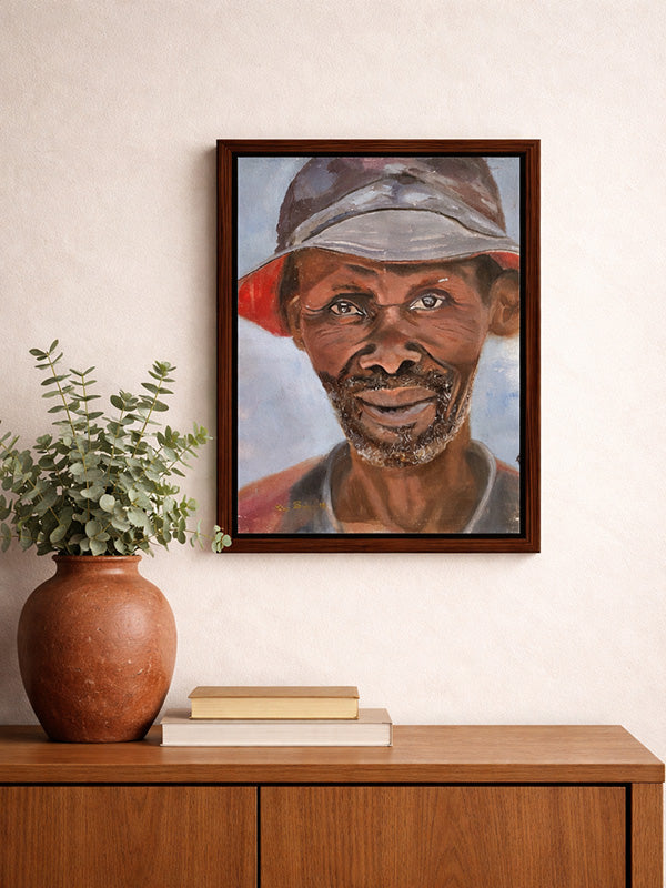 Framed portrait of a man with a cap on a wall above a wooden cabinet with a plant and books.