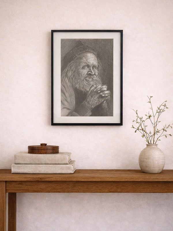 Framed black and white portrait of an elderly man on a wall above a wooden console table with books and a vase.