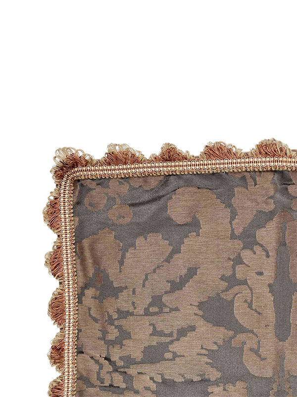 Decorative pillow with intricate pattern and tassel trim on a white background