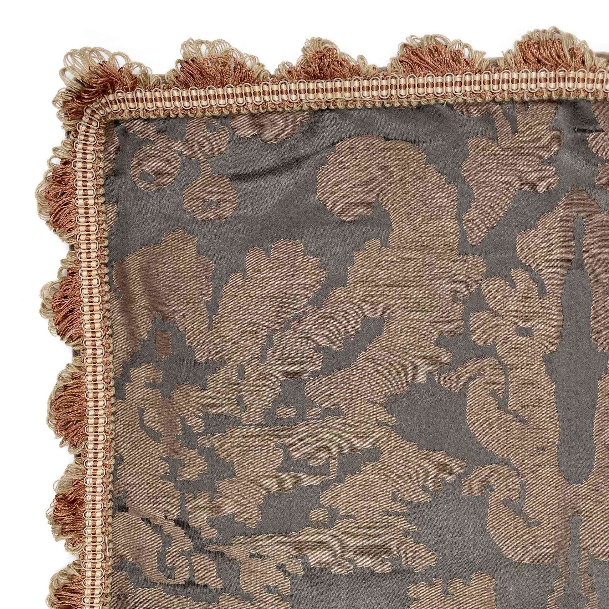 Decorative pillow with floral pattern and tassel trim on a white background