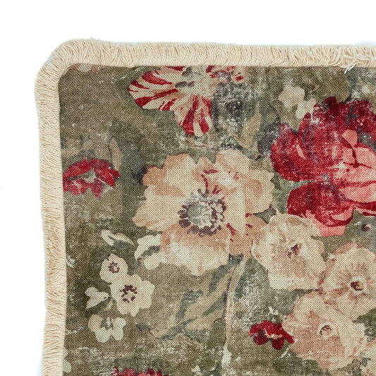 Floral patterned rug with red and beige flowers on a green background