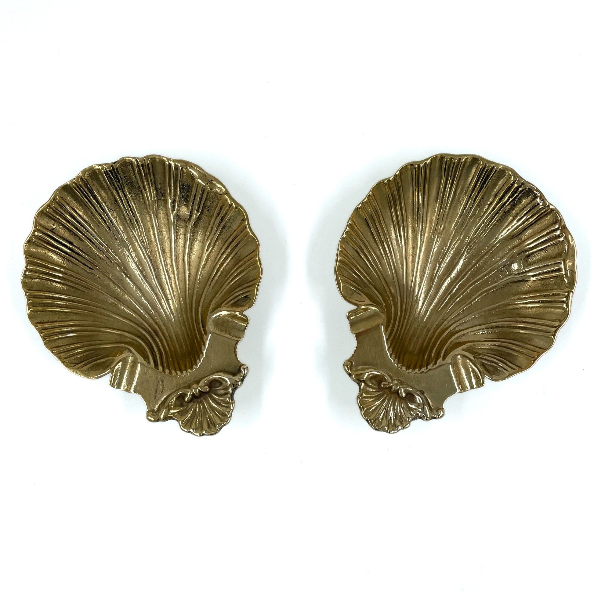 A pair of vintage shell dishes ,cast in gleaming brass with softly scalloped edges and ornate detailing at the base.
