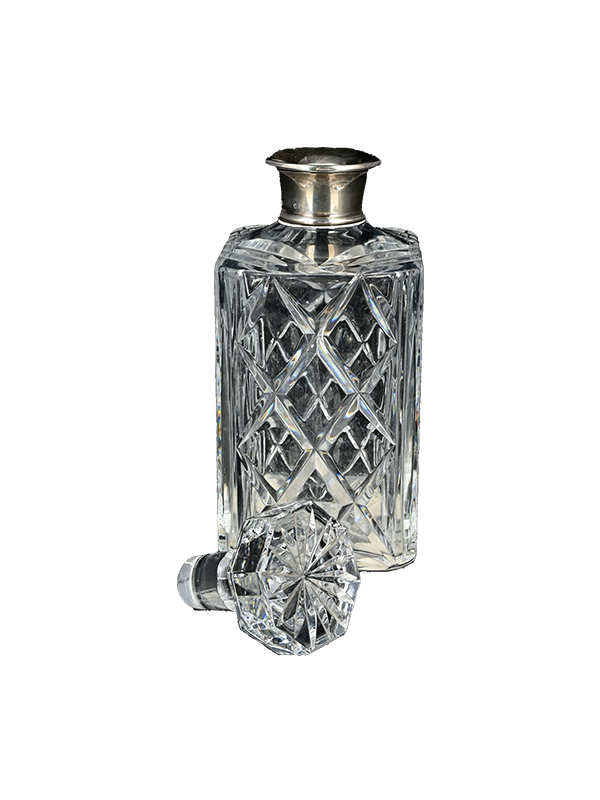 Vintage crystal decanter with silver collar on a white background
