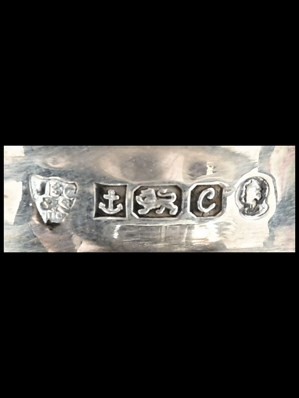 Close-up of silver hallmark on a crystal decanter collar, on a black background