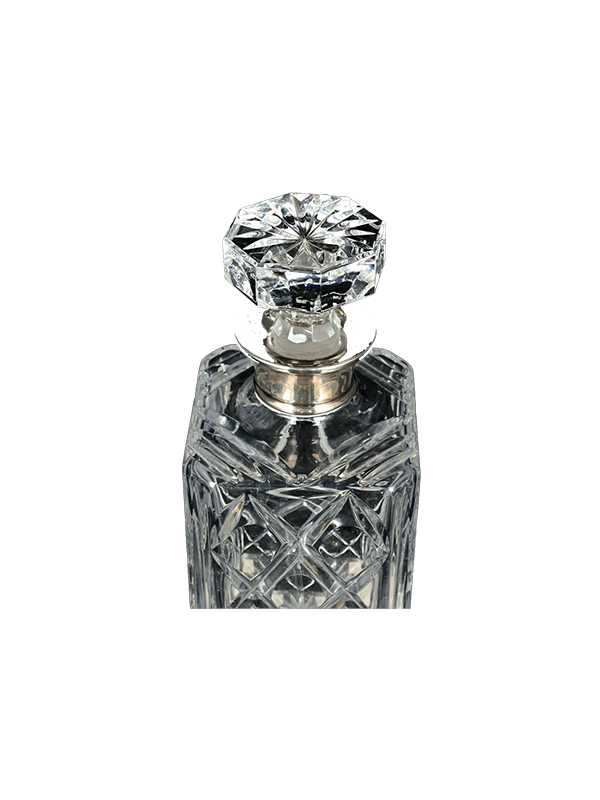 Vintage crystal decanter with a silver cap on a white background